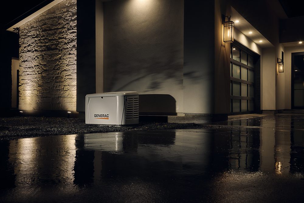 Generac standby generator outside a lit home during a night-time power outage